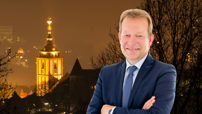 Bürgermeister Steffen Mues; im Hintergrund die beleuchtete Nikolaikirche zur Abendstunde