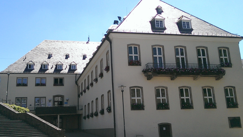 Frontalansicht des Rathauses in der Siegener Oberstadt mit Blumenkästen an den Fenstern. 